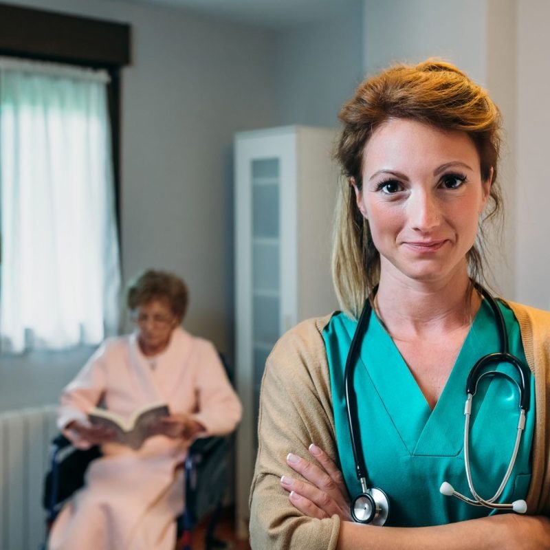 Pretty female doctor posing in a geriatric clinic with elderly lady in a wheelchair